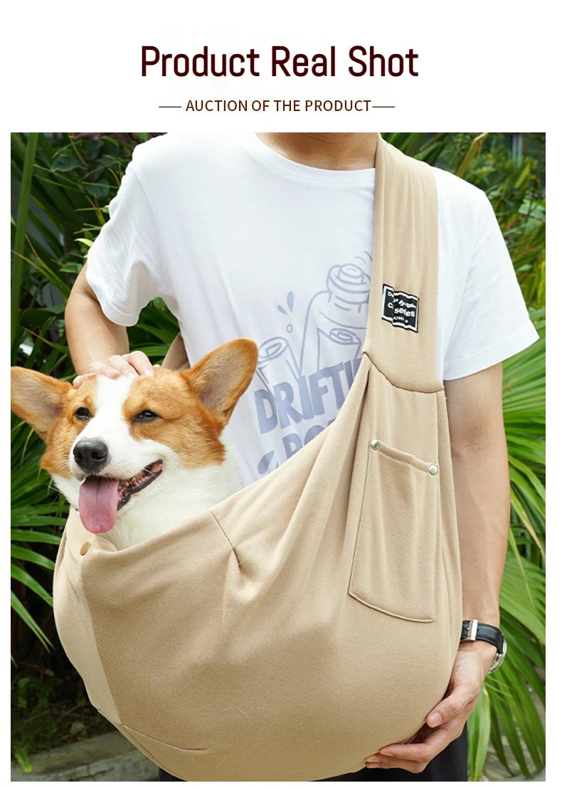 A person is holding a beige portable pet carrier sling bag with a dog's head peeking out.