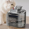 A white cat is drinking water from a clear pet water fountain bowl.