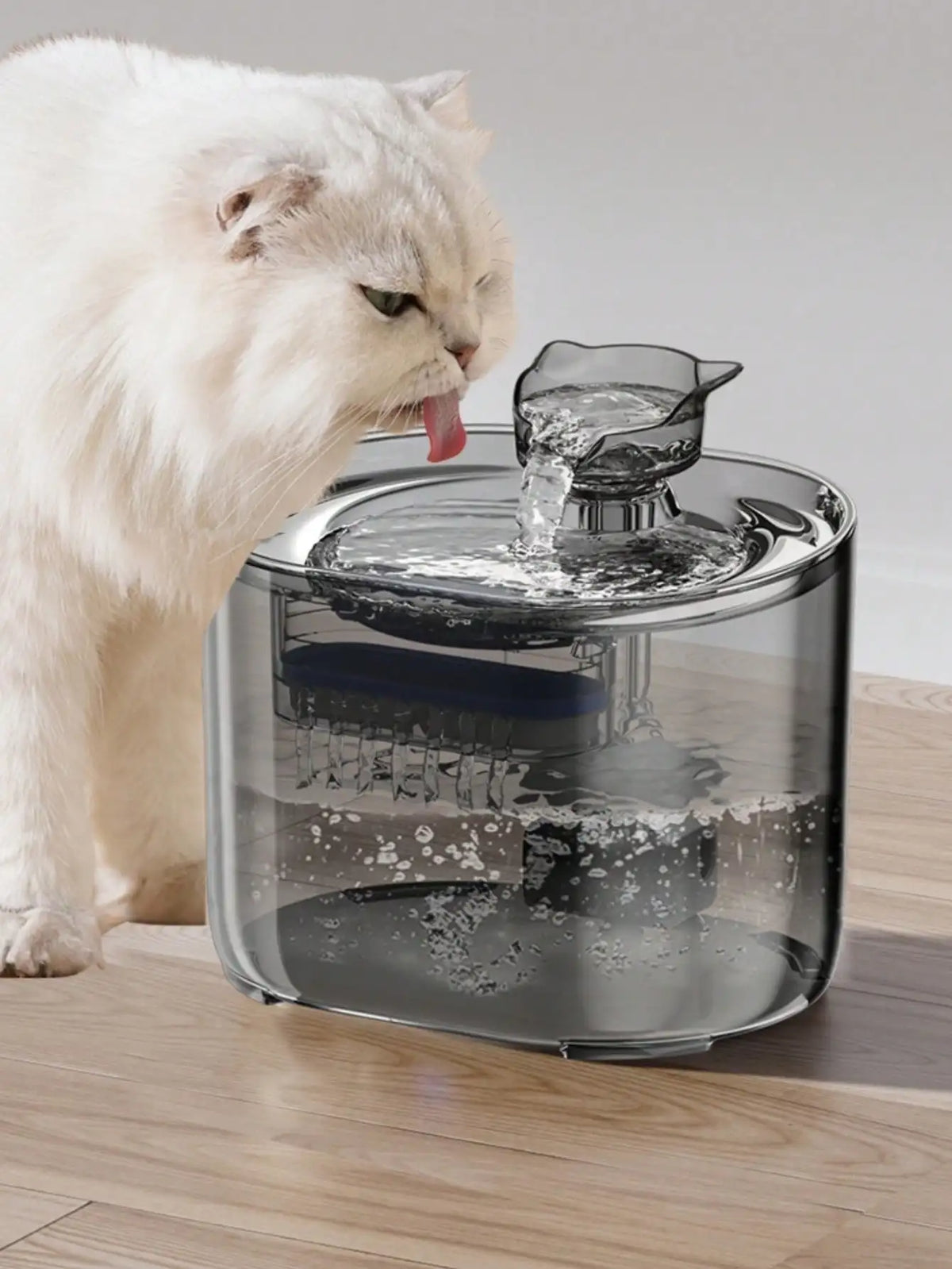 A white cat is drinking water from a clear pet water fountain bowl.