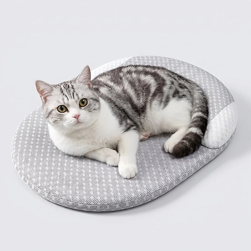A fluffy gray and white cat is resting on a light gray, textured pet bed.