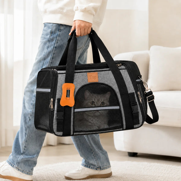 A person holds a black breathable mesh pet carrier bag with orange accents while standing indoors.