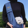 A person is wearing a blue pet shoulder bag while standing outdoors.
