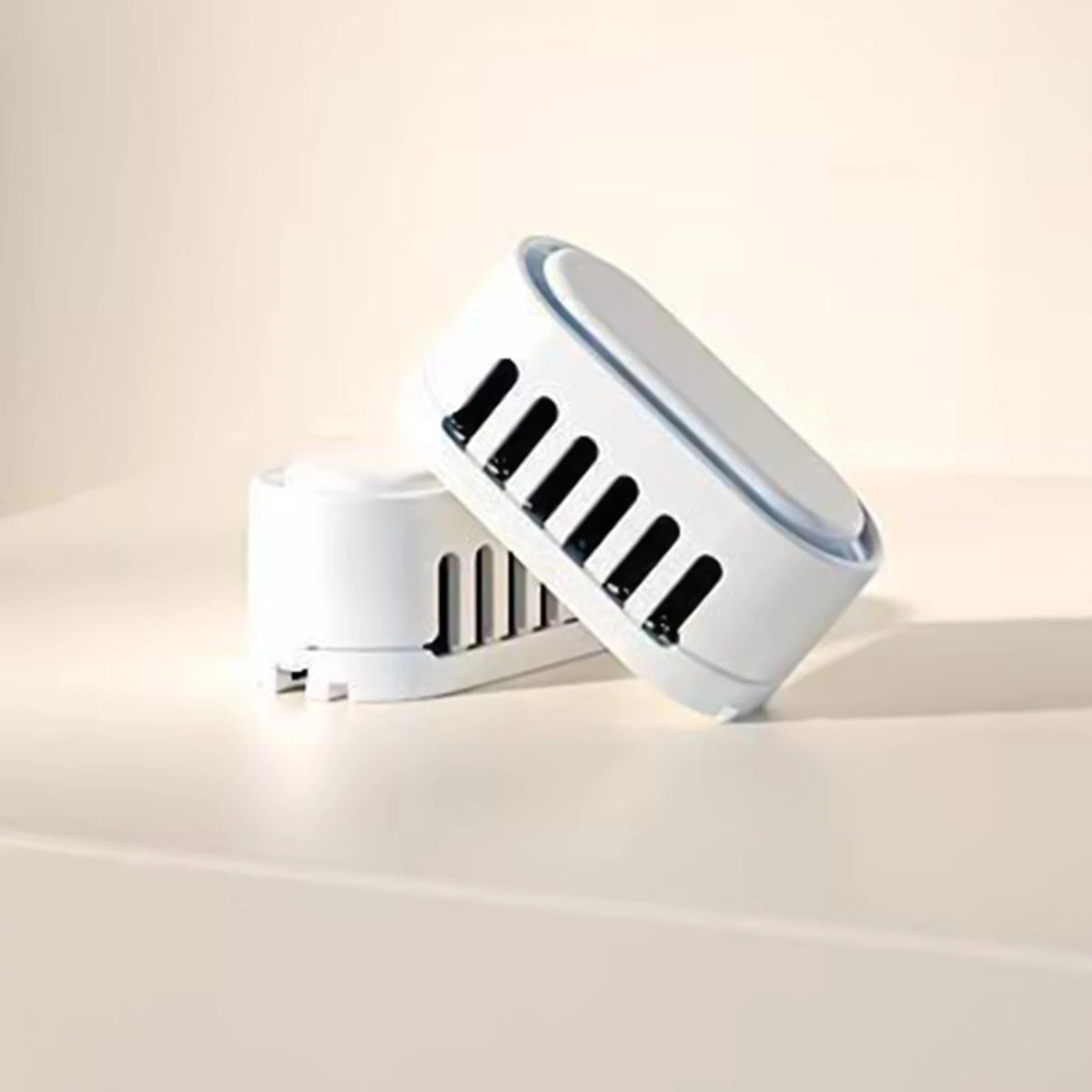 A white smart cat litter box deodorizer with a slotted design is shown on a light surface.