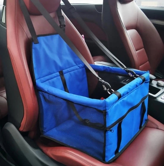 Un siège de transport pour animaux bleu et pliable est installé sur le siège arrière d'une voiture.