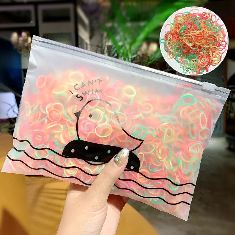 Eine durchsichtige Plastiktüte mit farbenfrohen, wiederverwendbaren Gummibändchen vor pink-orangefarbgem Hintergrund wird von