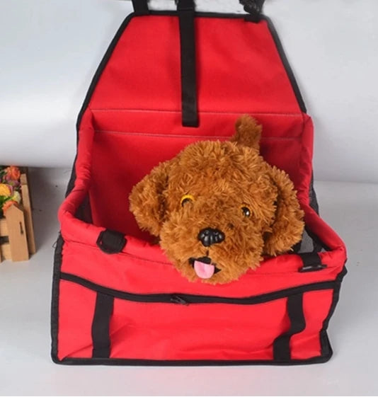 Siège de transport pliable pour animaux rouge avec sangle noire et ours en peluche marron à l'intérieur.