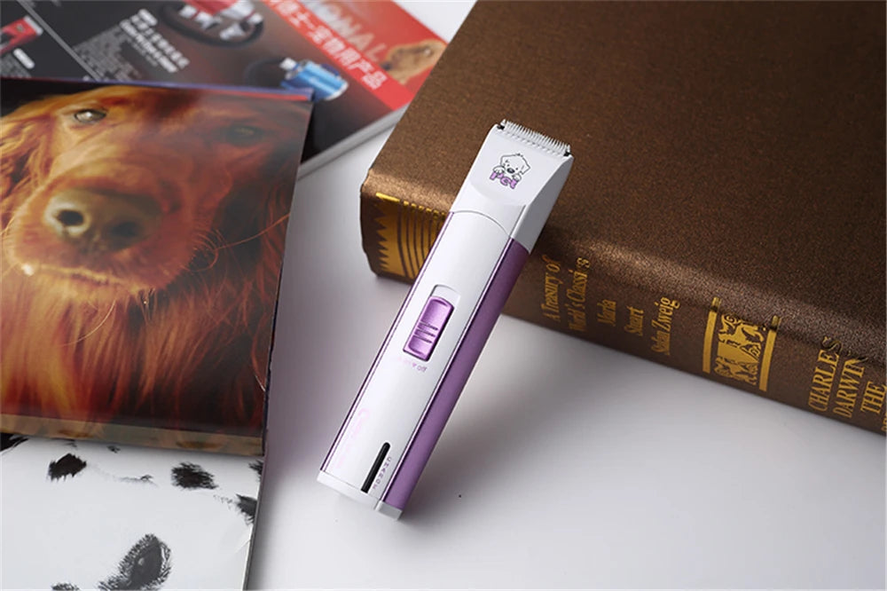 A white electric pet grooming clipper is placed on a brown book next to a picture of a dog.