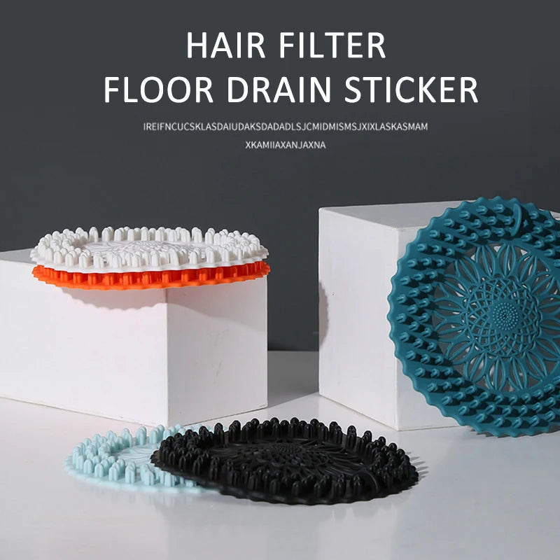 Various silicone drain stickers and covers in white, orange, blue, and black are displayed on a white surface.