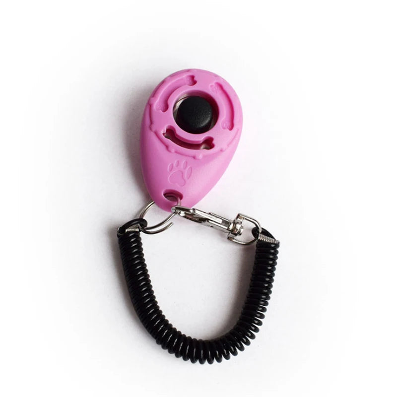 A pink pet training clicker with a paw print design attached to a black wrist strap.