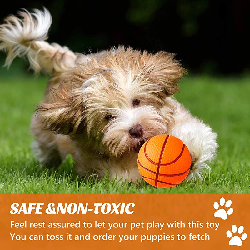 A fluffy light brown dog is lying down with an orange ball in its paw on green grass.