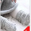 Gray knitted baby socks with animal cartoon designs resting on white fluffy fur.