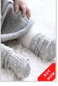 Gray knitted baby socks with animal cartoon designs resting on white fluffy fur.