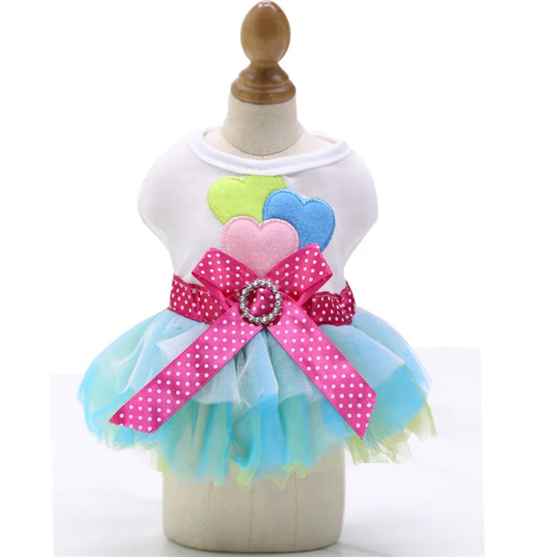 A white dress with pink and blue lace details and a tulle skirt displayed on a mannequin.