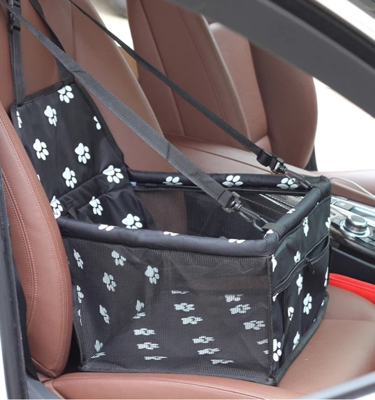 Siège de transport pliable en maille noire pour animaux installé dans un siège de voiture marron.