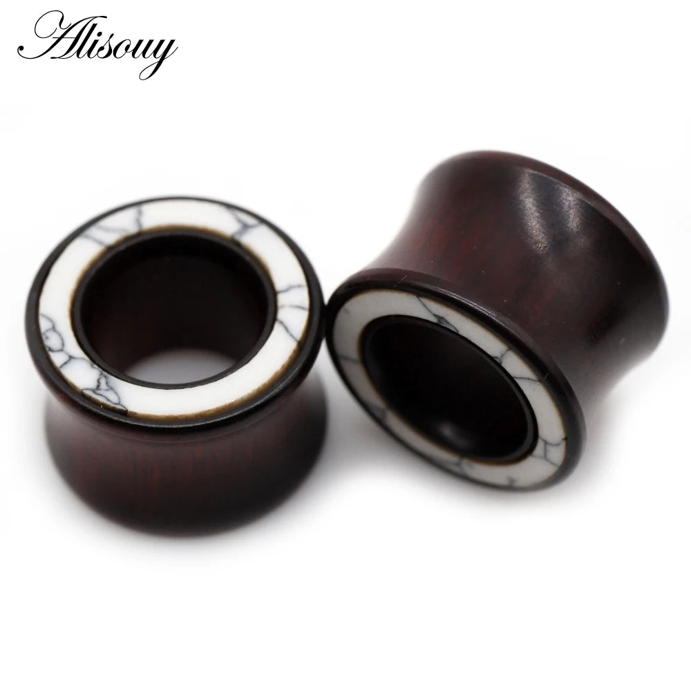 A pair of dark wood ear tunnels with white marble inlay visible against a white background.