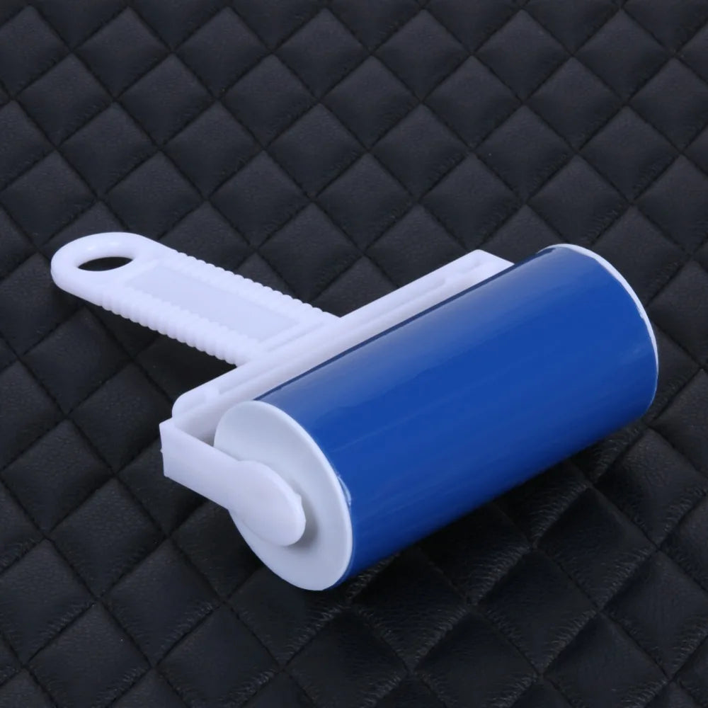 A blue reusable lint and pet hair roller with a white handle resting on a black quilted surface.