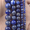 A hand holds multiple strands of natural blue and gray stone beads for jewelry making