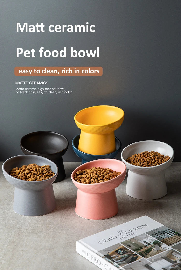 A collection of matte ceramic pet food bowls in various colors, including yellow, black, and pink, displayed on a gray surfac