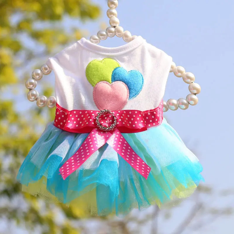A pink and blue lace dress for a pet featuring colorful fabric flowers and a tulle skirt.