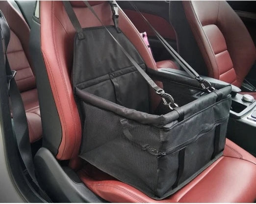 Un siège de transport pour animaux pliable noir est montré à l'intérieur d'un siège de voiture en cuir rouge.
