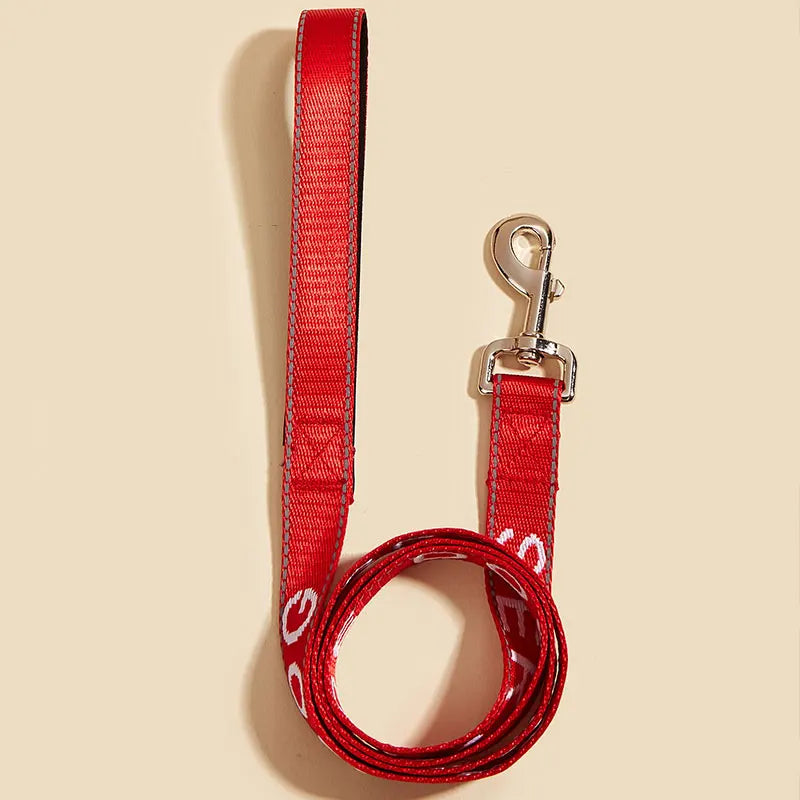 A bright red reflective service dog leash with a padded neoprene handle and metal clip.