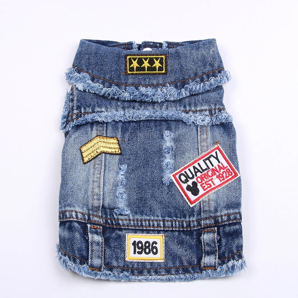 A blue denim jacket for dogs featuring distressed fabric and gold stitching.