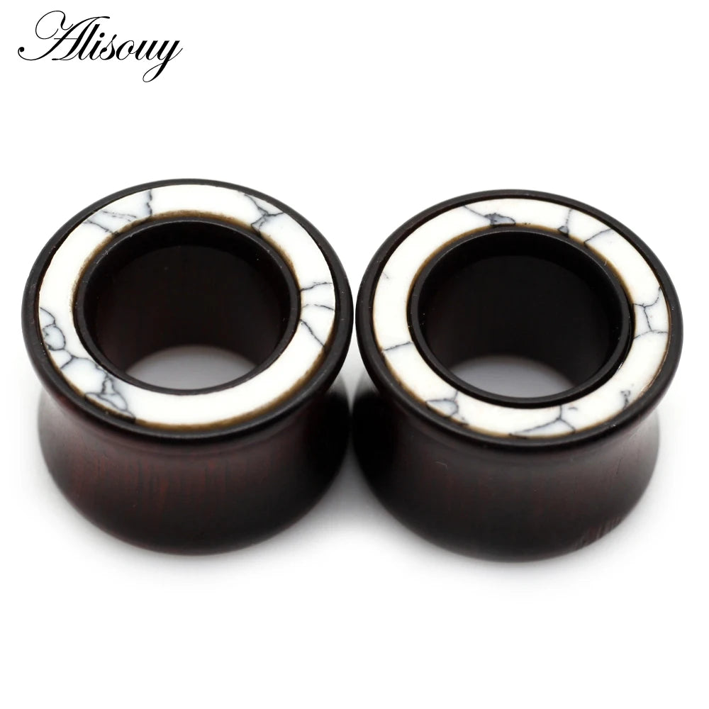 A pair of dark wood ear tunnels with white marble inlay.