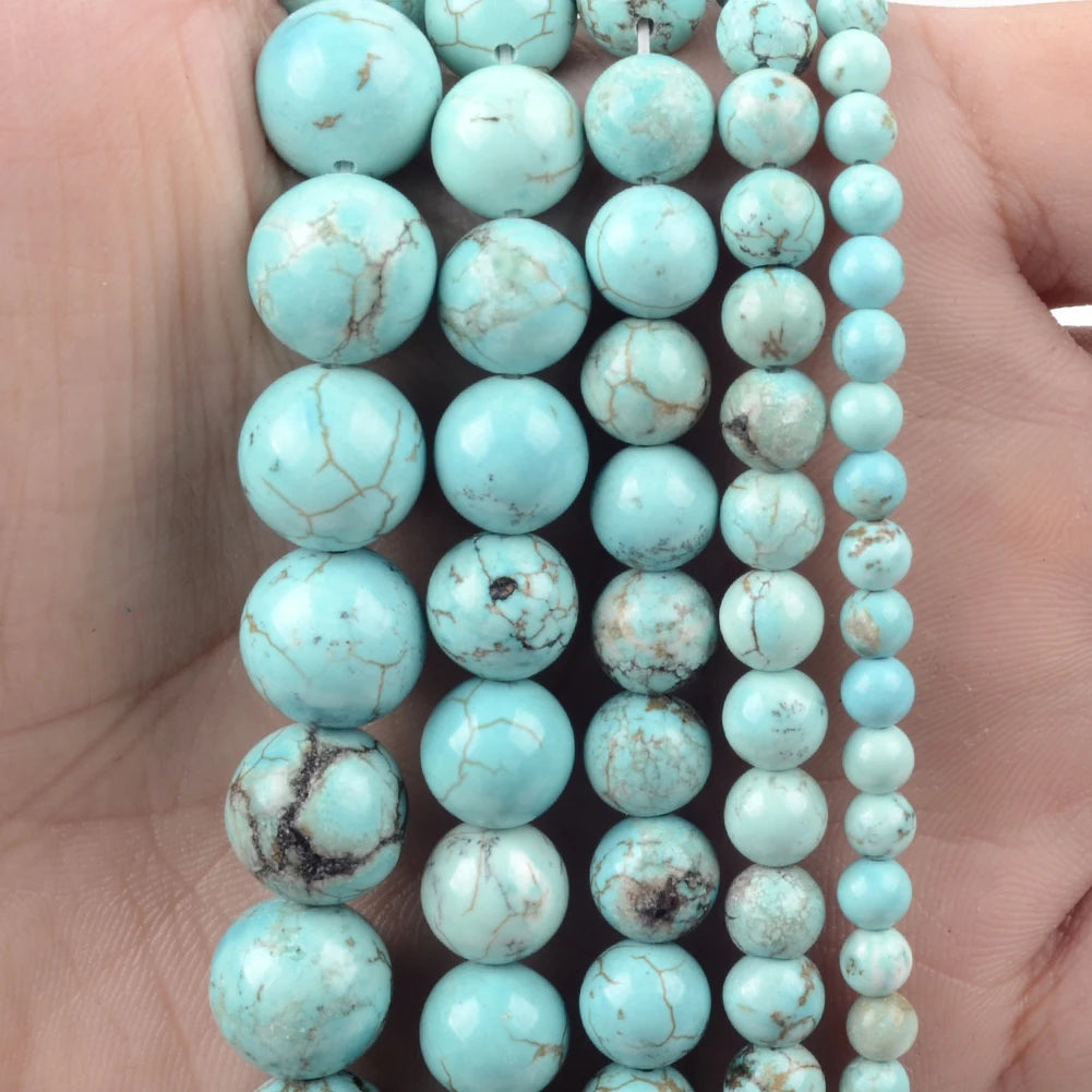A hand holds a strand of light blue turquoise natural stone beads for jewelry making