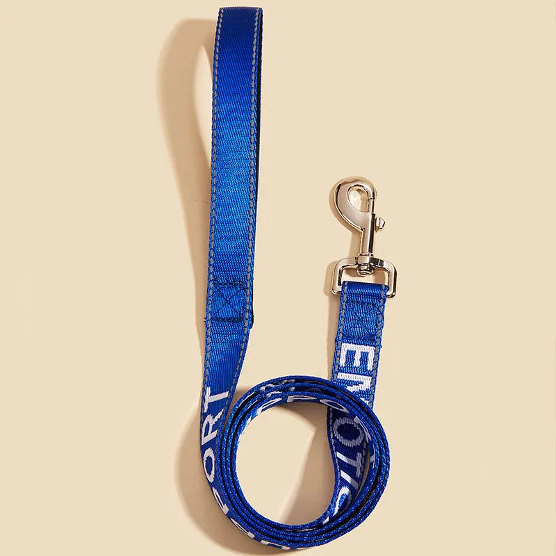 A blue reflective service dog leash with a padded neoprene handle hanging against a light background.