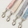 A collection of pink, beige, and gray fabric pet leashes or harnesses with metal clasps.