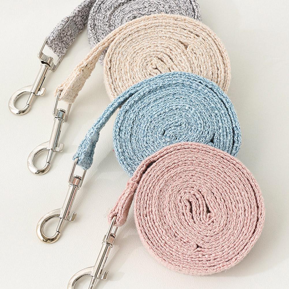 A stack of beige, gray, and blue braided pet leashes and harnesses.