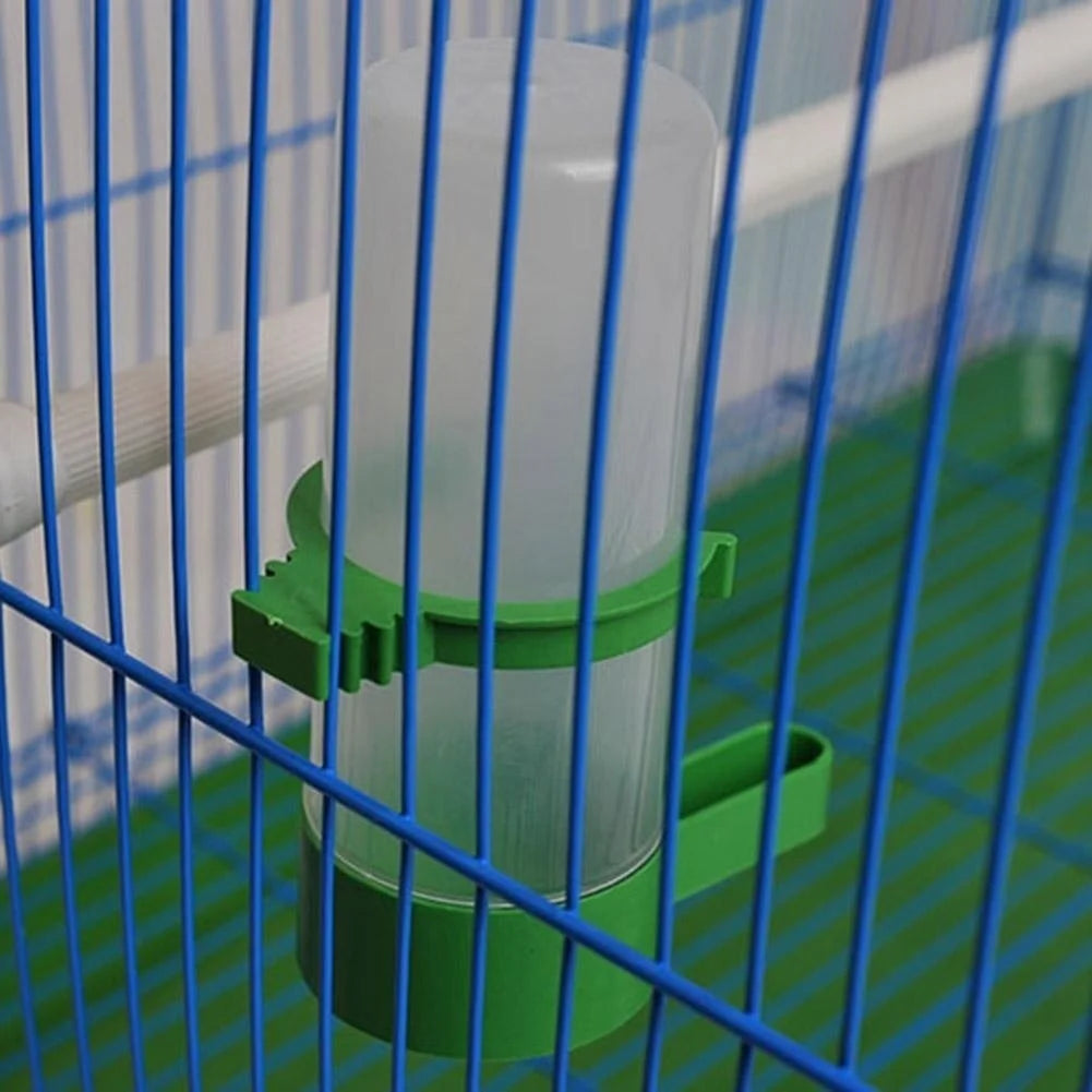A clear plastic clip-on bird feeder and waterer set with green components inside a blue wire cage.