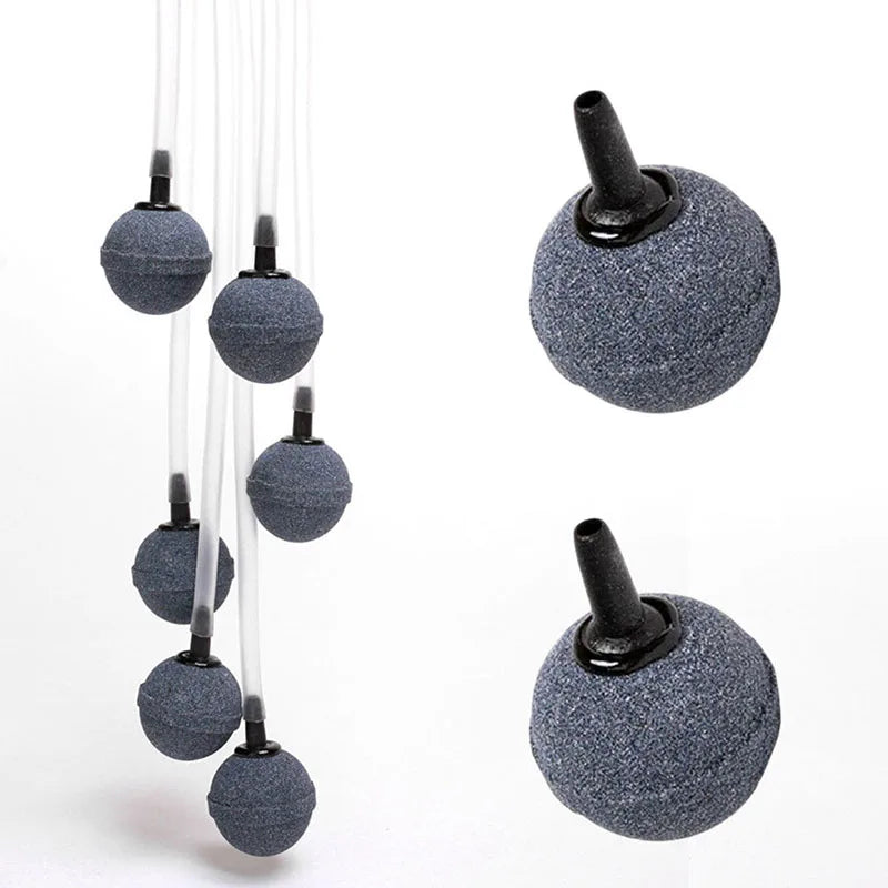 A set of five small, round, gray aquarium air stones with black nozzles shown against a white background.