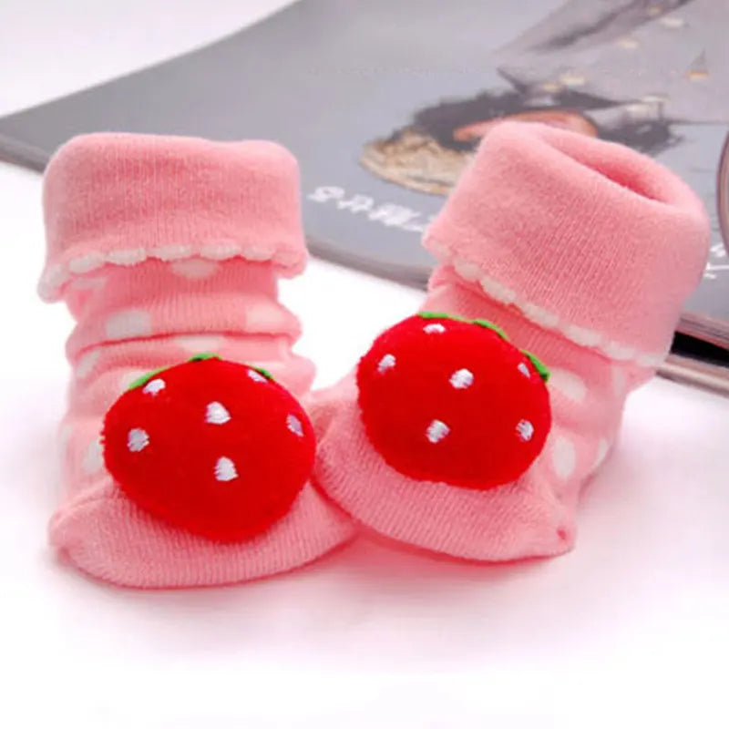 Pair of pink knitted baby socks with red strawberry designs for toddlers