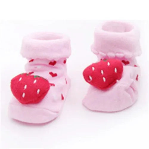 Pair of pink fuzzy baby socks with red strawberry patterns for toddlers