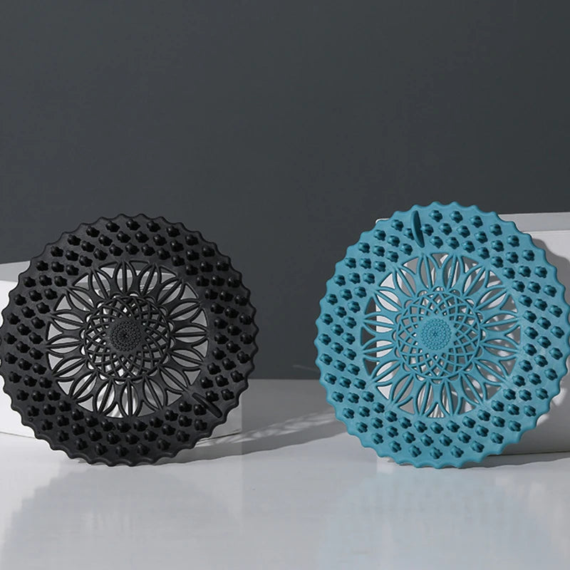 A black silicone drain cover with a decorative pattern and a teal silicone drain cover with a similar pattern.