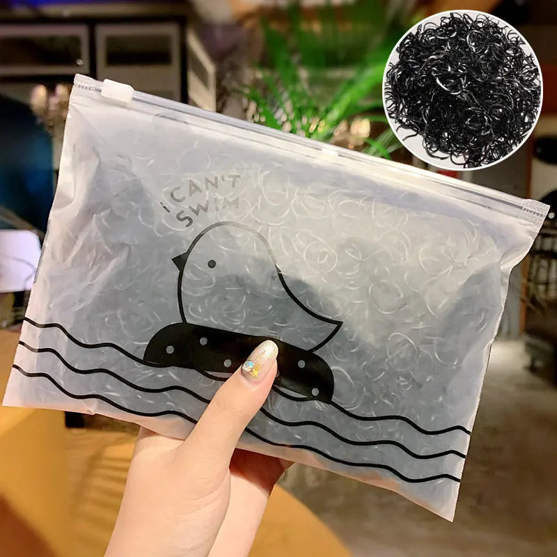 Eine Hand hält einen durchsichtigen Plastetüte mit schwarzen Gummihaarbinden in Form einer schwimmenden Ente.