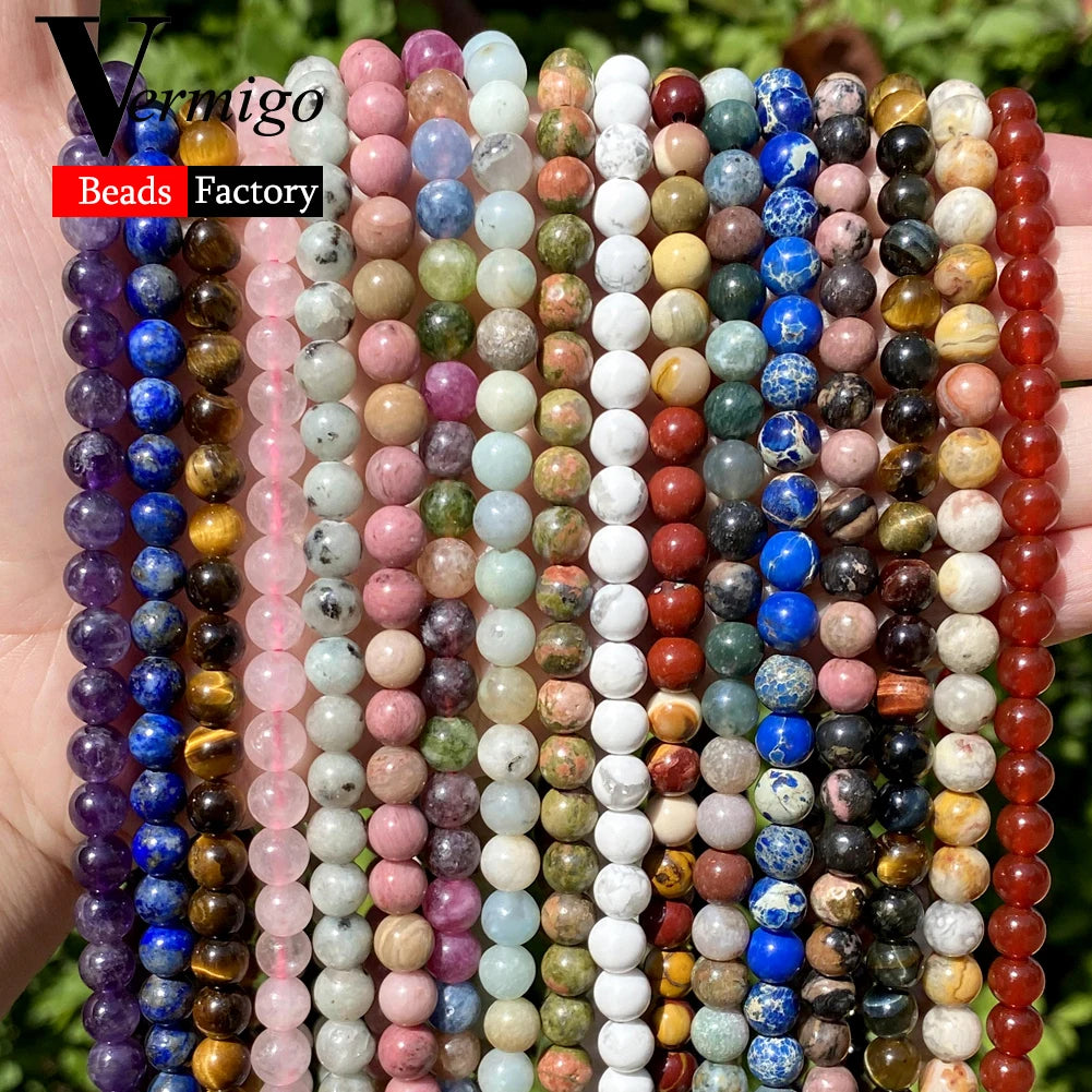 A close-up of numerous strands of colorful natural stone beads for jewelry making displayed in a hand.
