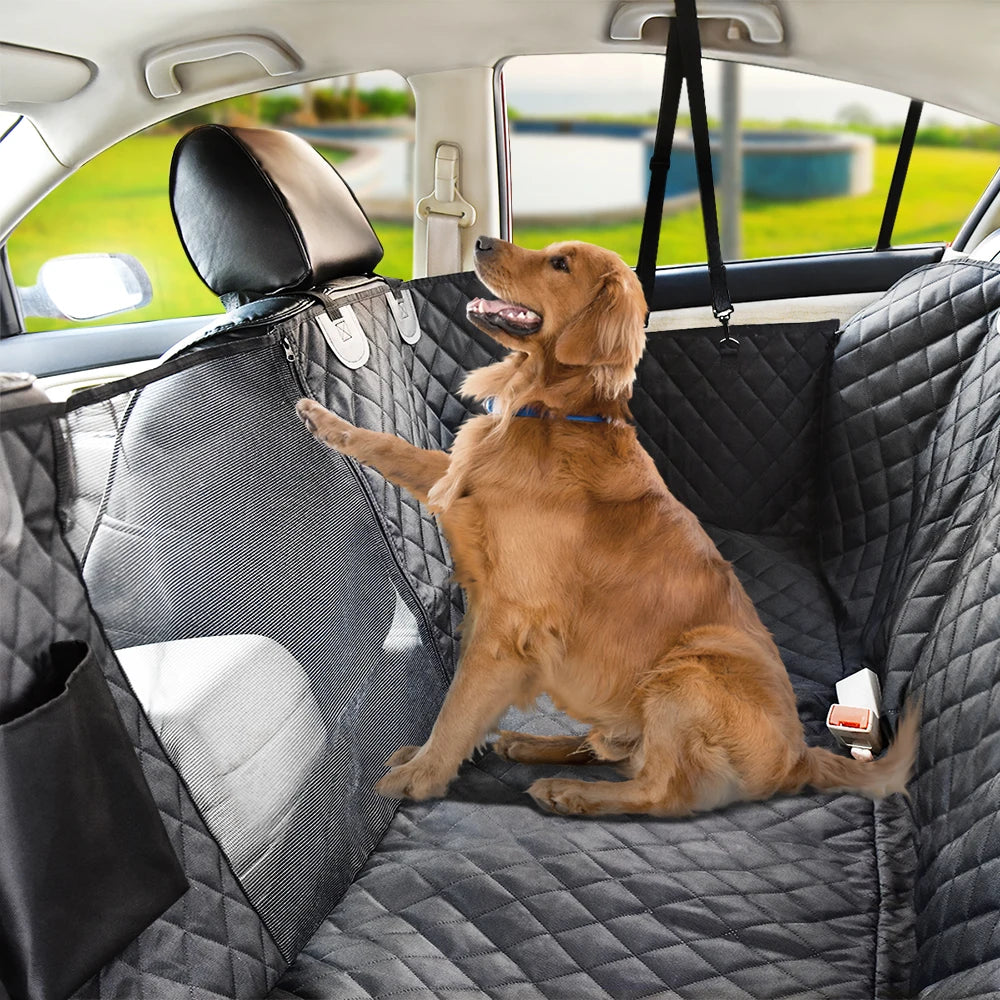 A golden retriever sits in a black waterproof dog car seat cover with a hammock and mesh window.