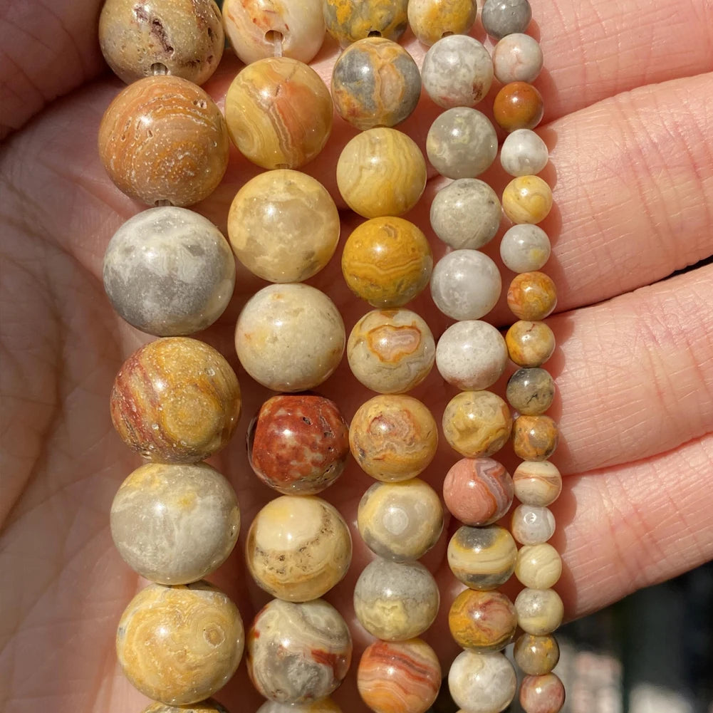 A string of natural stone beads in various colors and sizes is held in a hand.