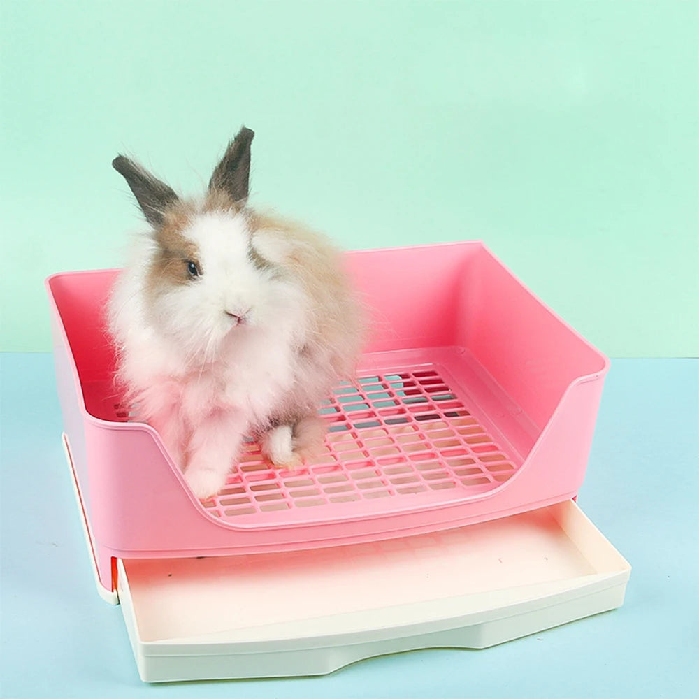 A fluffy white rabbit is sitting inside a pink anti-overturn drawer litter box.
