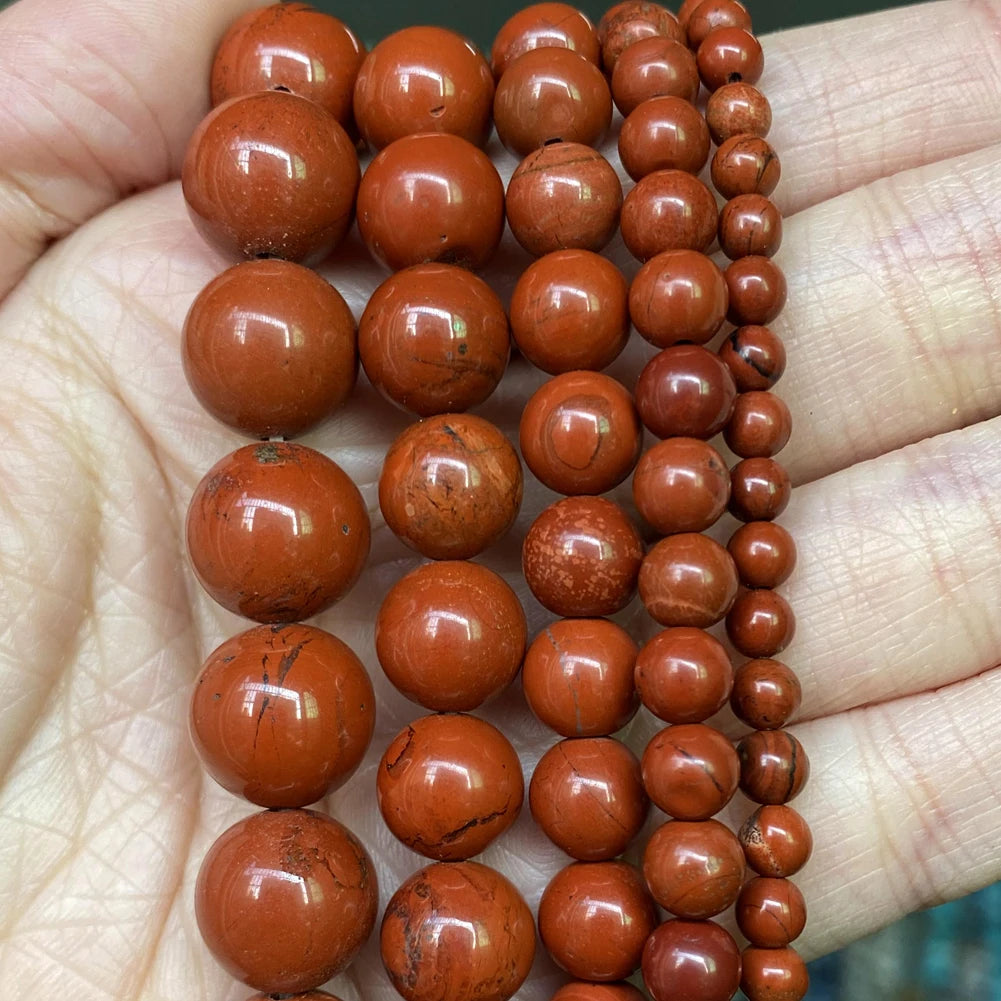 A string of natural reddish-brown stone beads for jewelry making, showing various sizes and styles.