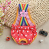 A colorful washable physiological dog underwear featuring rainbow stripes and a pink flower, displayed on a woven mat.