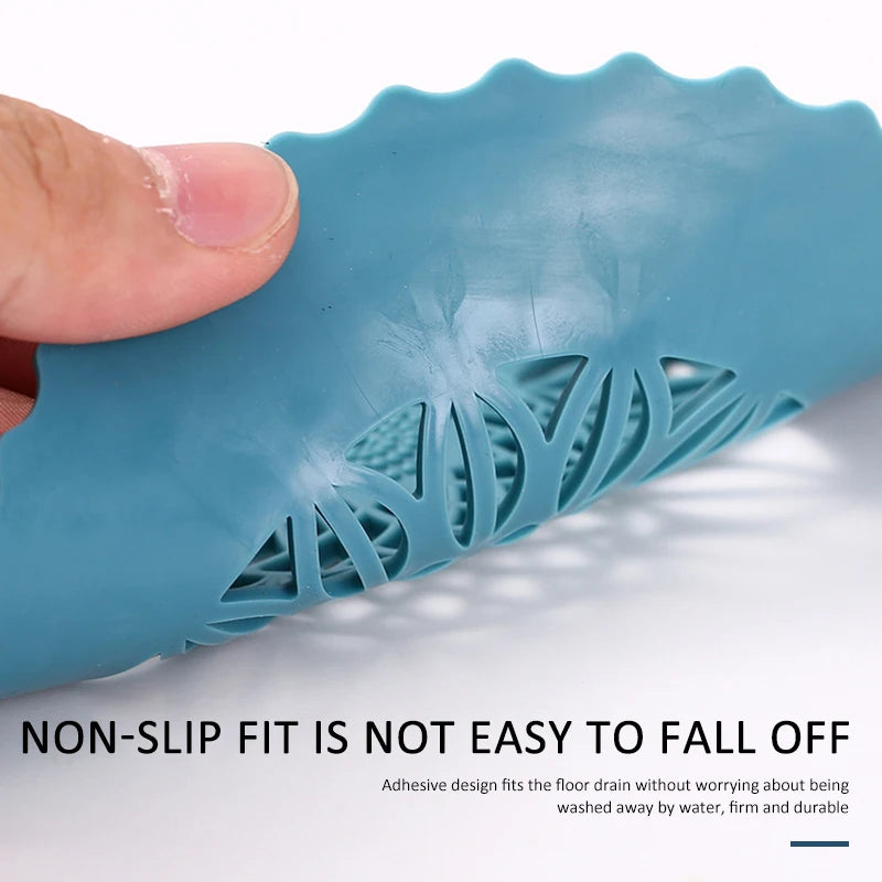 A hand holds a blue silicone drain cover with a handle, demonstrating its non-slip fit for floor drains.