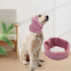A light-colored dog is wearing a soft mauve ear muff for comfort and noise reduction.