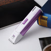 A purple and white electric pet grooming clipper is shown next to a book on a white surface.