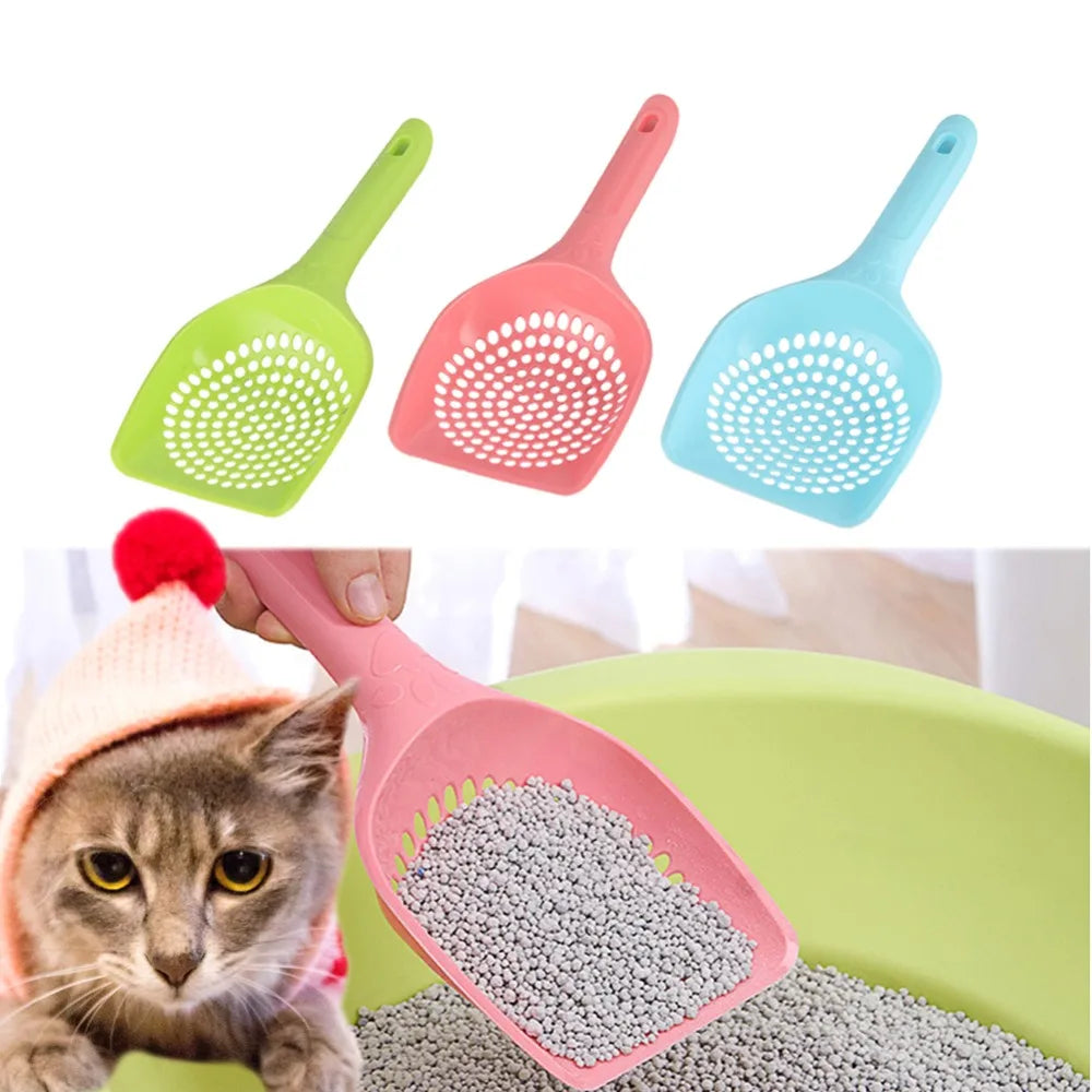 Three plastic pet litter scoops in green, pink, and blue next to a hand holding a pink scoop filled with gray pet litter.
