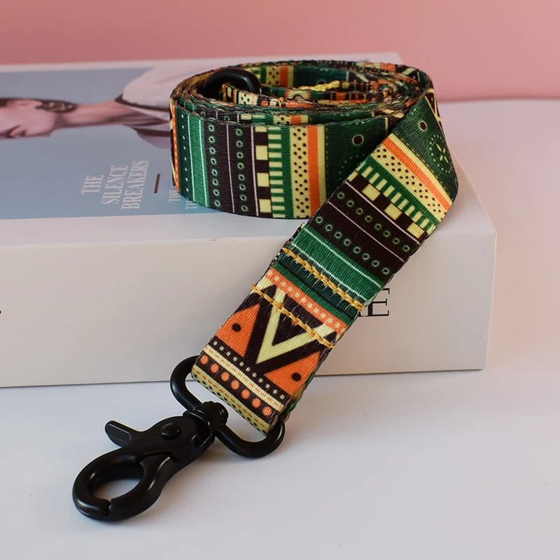 A patterned fabric dog collar and leash set with green, black, and orange designs resting on a white box.
