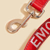 A close-up of a red reflective service dog leash with a silver metal clip and padded neoprene handle.