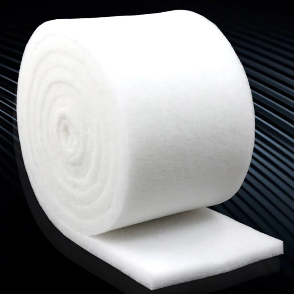 A roll of white dual-density aquarium filter sponge resting on a dark surface.